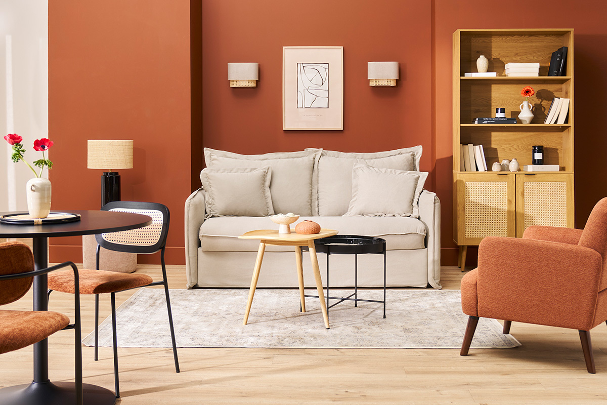 Salon avec applique murale en lin beige et rotin sur mur terracotta, canap� beige et mobilier en bois.