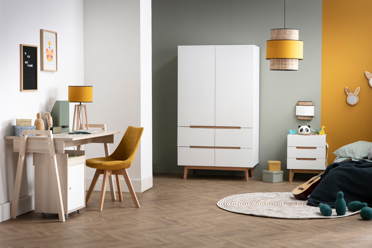 Armoire scandinave blanche avec tiroirs, � c�t� d'un bureau en bois et objets d�coratifs.