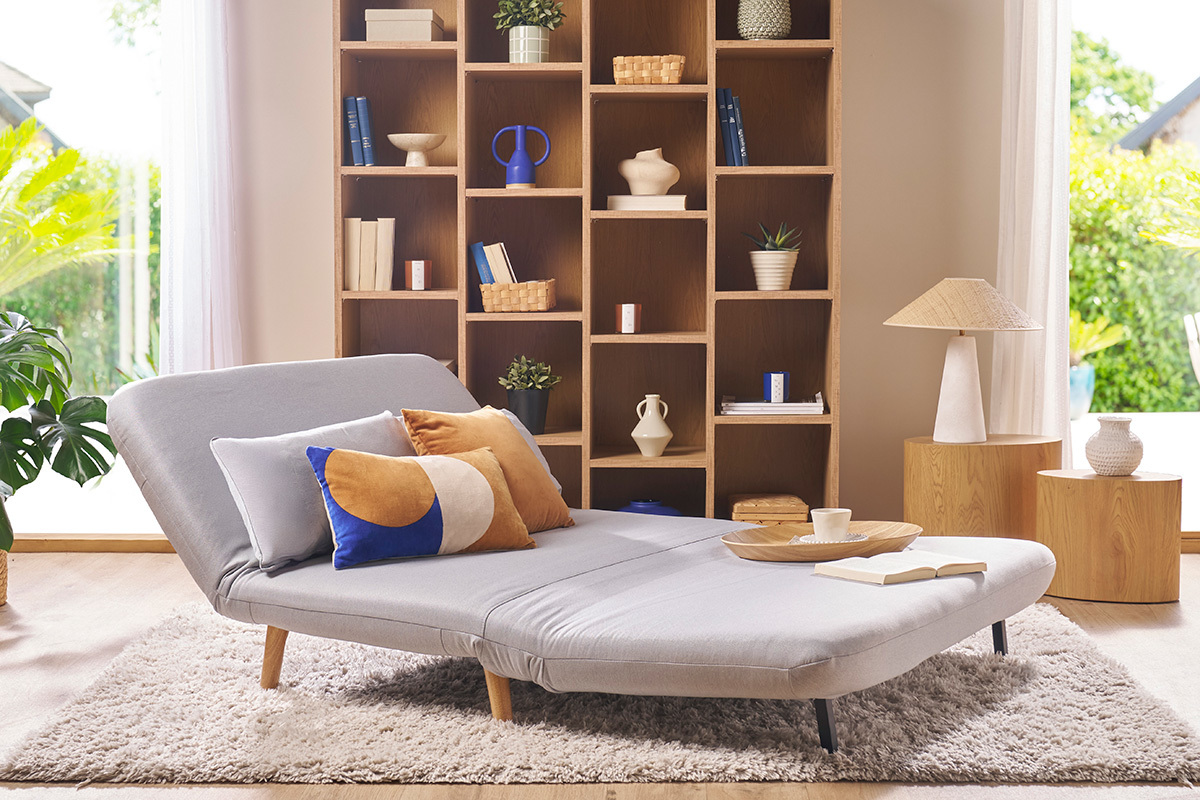 Banquette convertible 2 places AMIKO en tissu gris clair avec coussins d�coratifs, vue de trois quarts