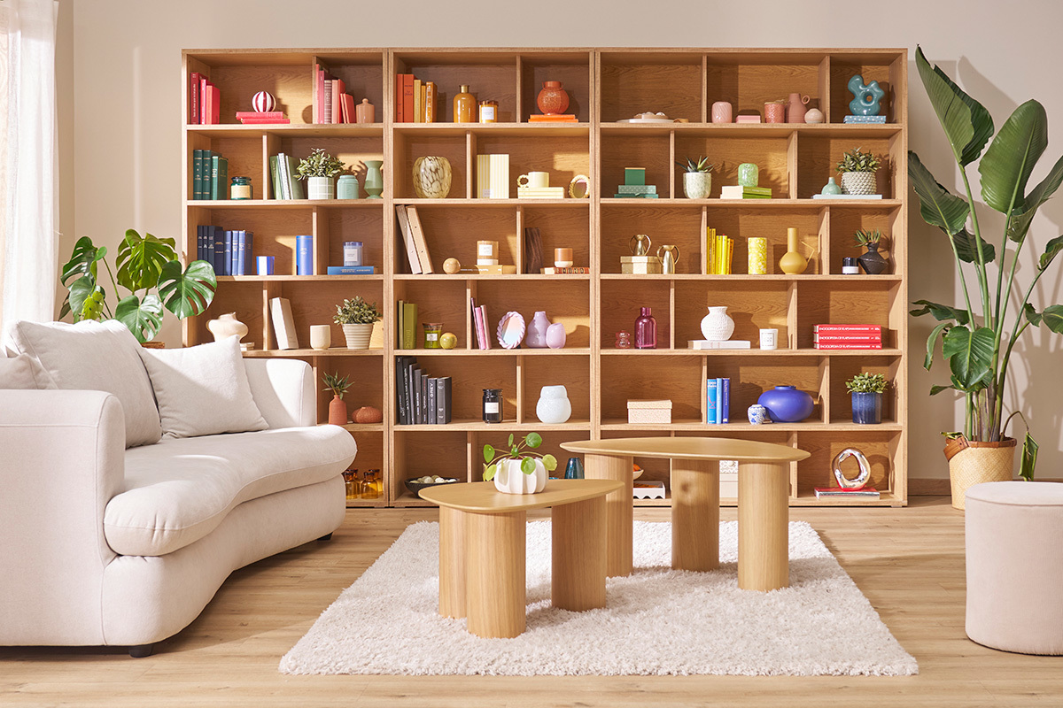Biblioth�que scandinave en bois clair avec objets d�co et canap�s, vue de face.