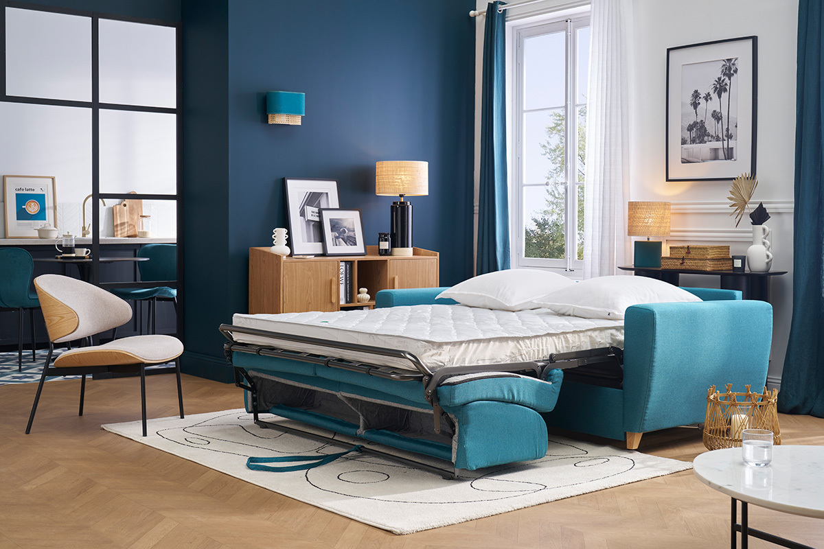 Canap� convertible bleu canard ouvert avec matelas dans un salon moderne.