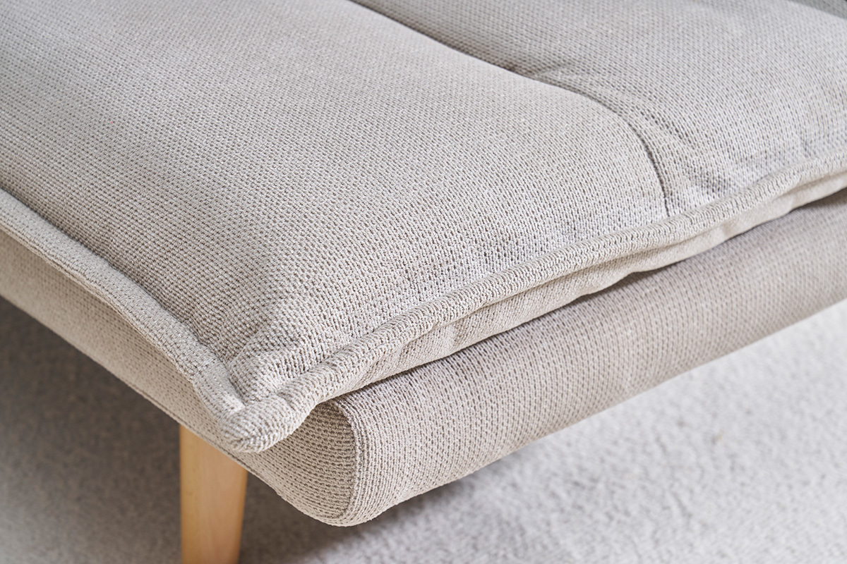 Gros plan d'un canap� convertible en tissu chenille beige avec pieds en bois clair.