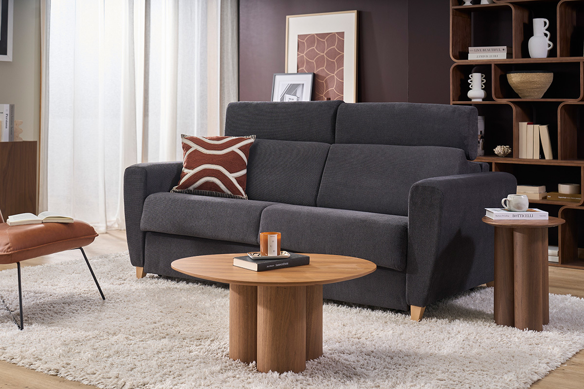 Canap� convertible 3 places gris anthracite avec t�ti�res ajustables, vue de face, d�cor� avec table et coussin.
