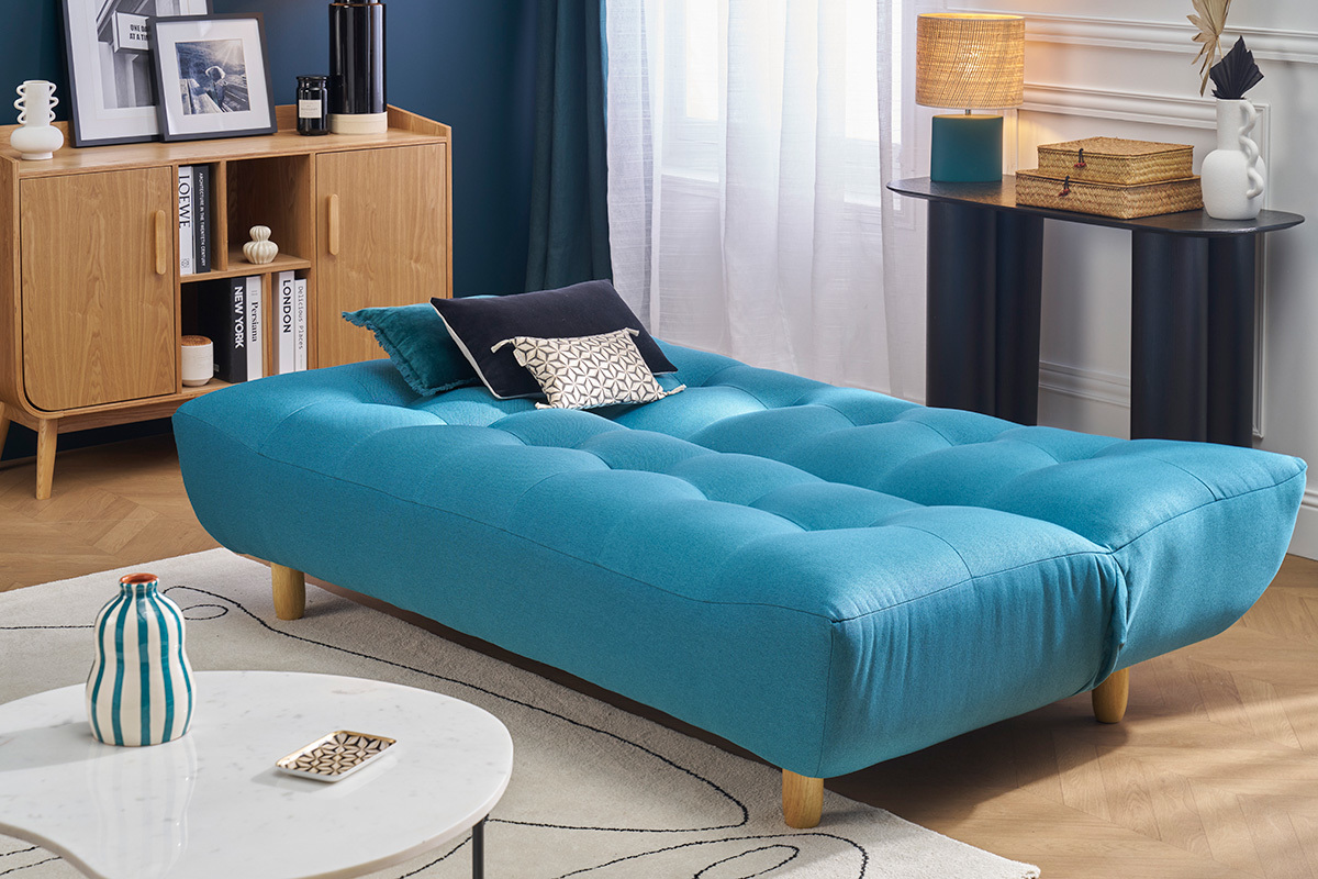 Canap� convertible scandinave bleu canard avec pieds en bois, vu de c�t� dans un salon.
