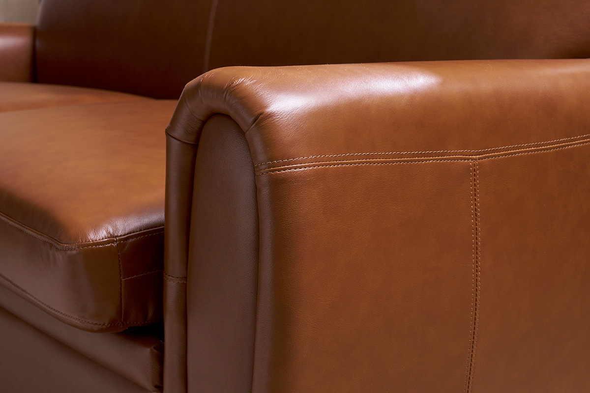 D�tail du canap� convertible vintage 3 places en cuir marron, vue rapproch�e de l'accoudoir.