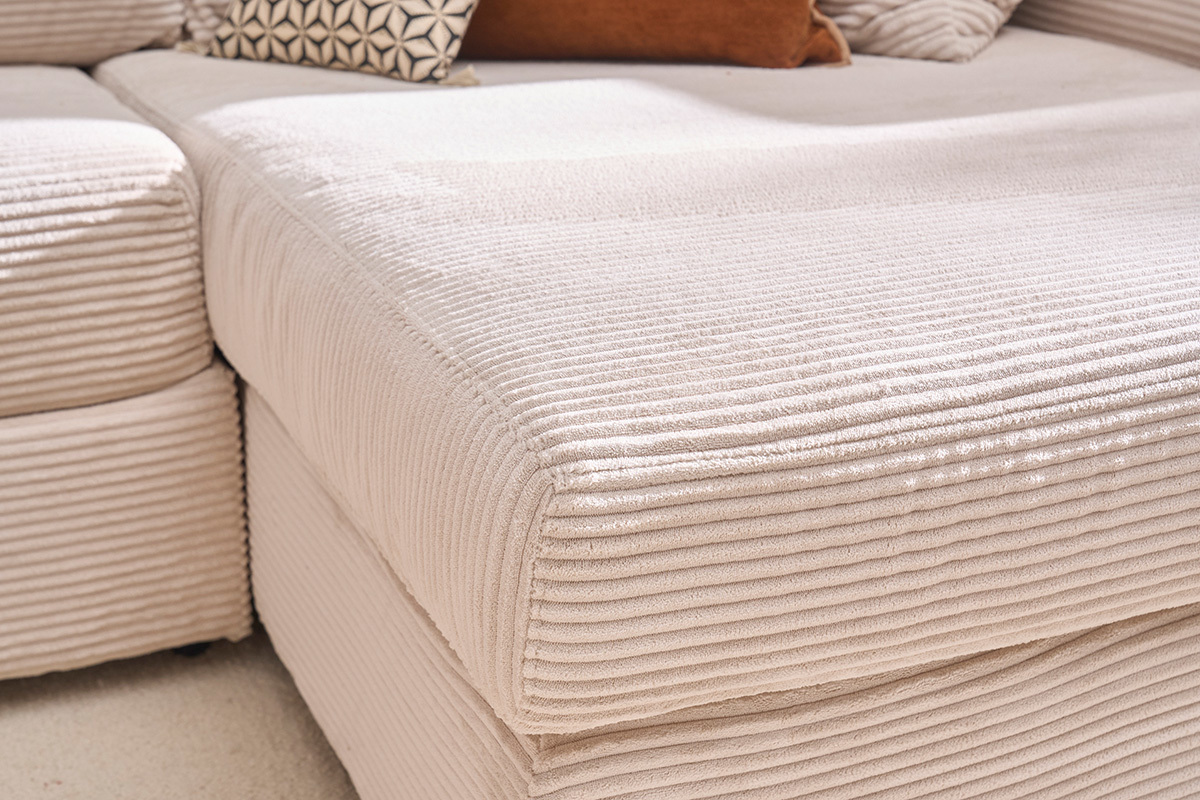 Gros plan sur un canap� en velours c�tel� beige avec coussins d�coratifs.