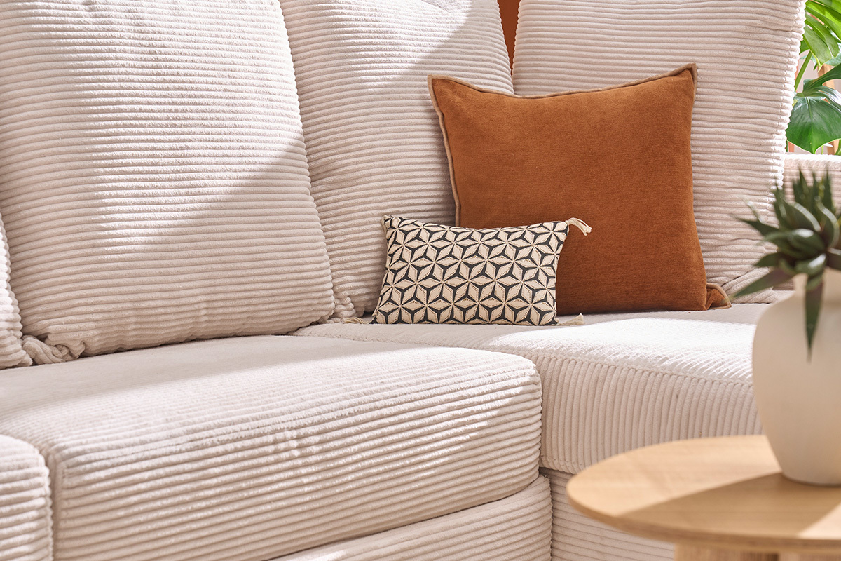 Canap� d'angle beige en velours c�tel� avec coussins d�coratifs vu de c�t�.