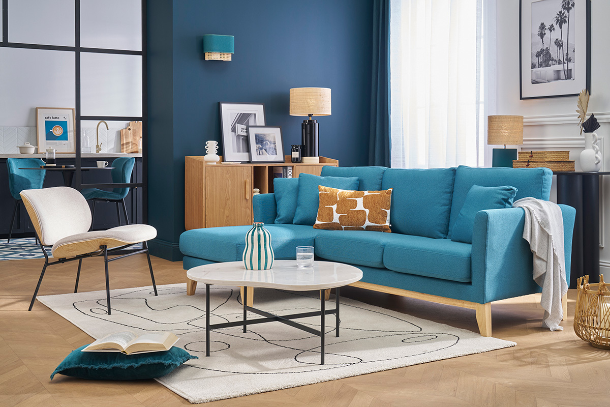 Salon avec canap� d'angle bleu canard OSLO, table basse blanche et fauteuil beige.