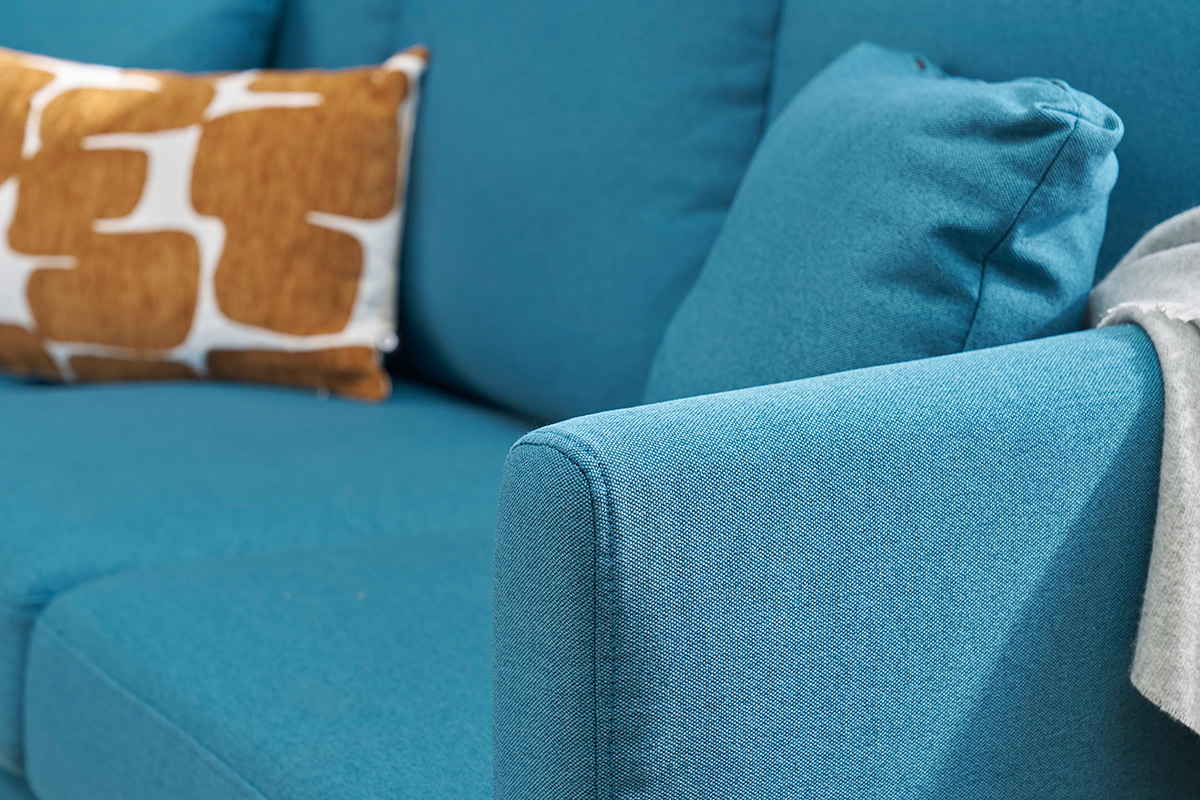 Gros plan sur un canap� d'angle bleu canard avec coussins.