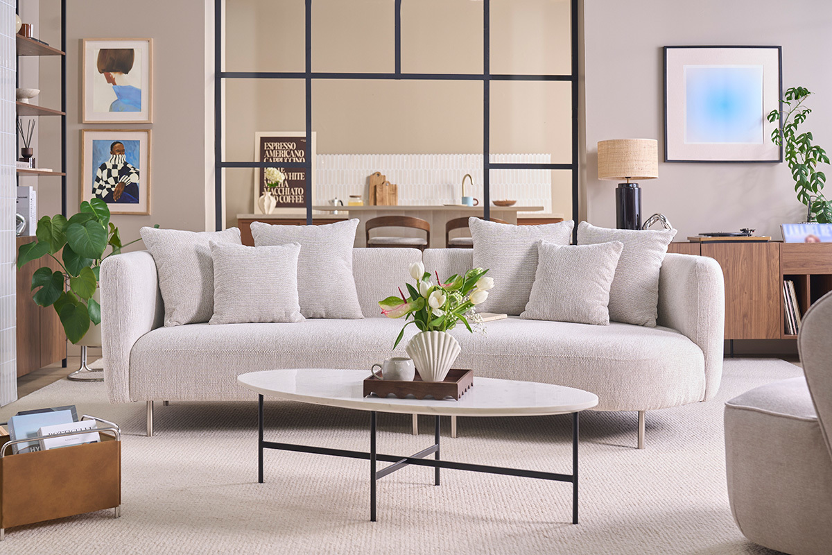 Canap� design 3-4 places en tissu beige clair avec coussins, vue de face.