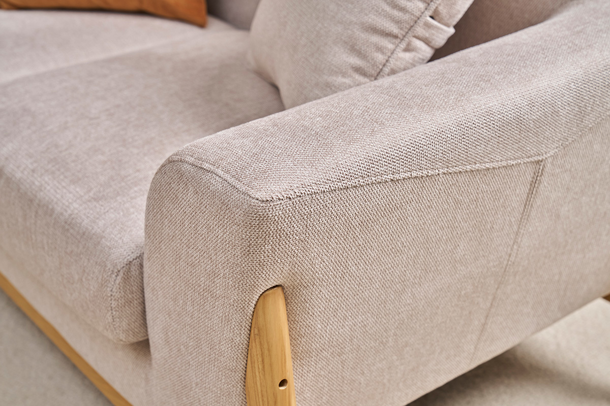 D�tail d'un canap� scandinave en tissu effet velours beige et bois clair.