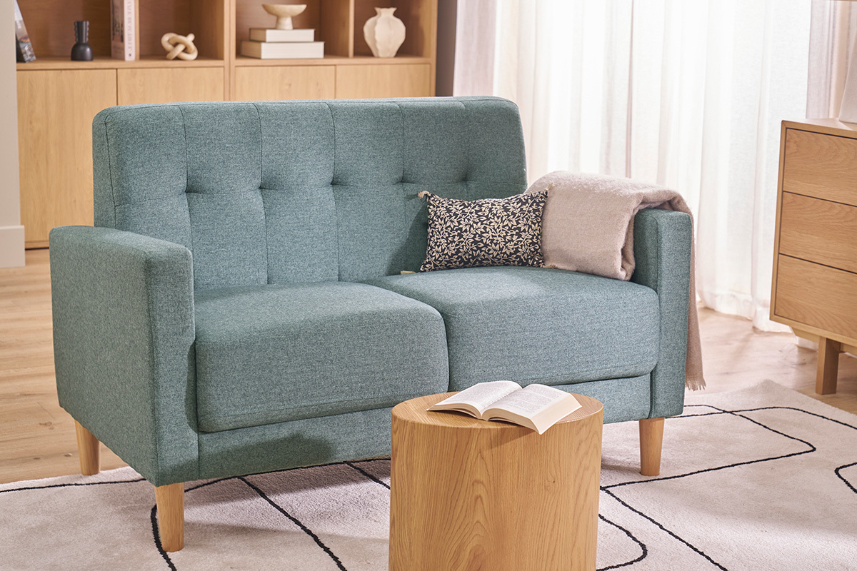 Canap� scandinave 2 places vert de gris en tissu et bois clair, vu de face avec coussin et plaid.