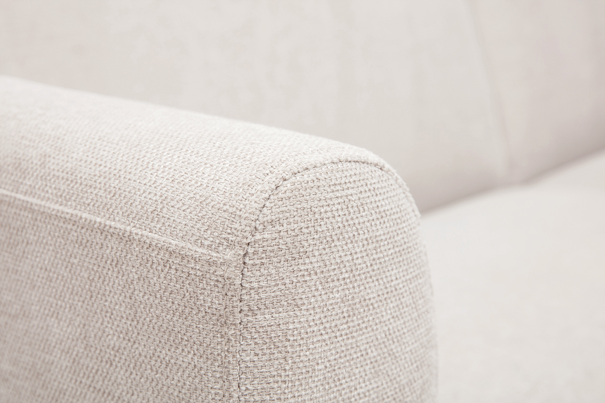 Gros plan sur l'accoudoir d'un canap� en tissu effet velours textur� beige.