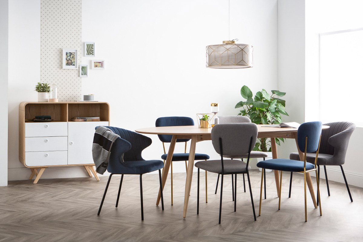 Salle � manger avec des chaises en tissu velours bleu fonc� et m�tal noir autour d'une table en bois.