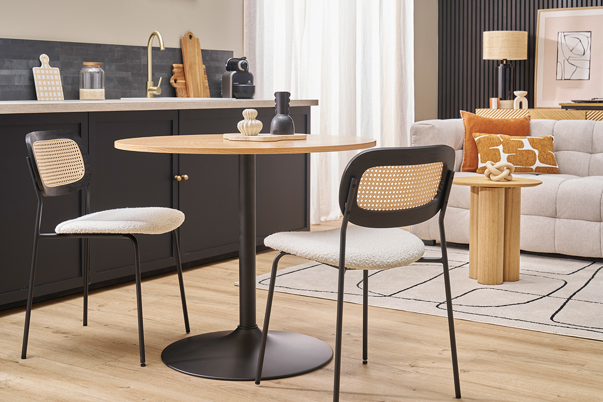 Deux chaises en tissu boucl� blanc et m�tal noir avec dossier en cannage, autour d'une table ronde en bois.