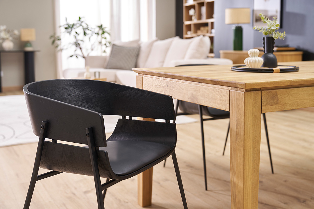 Chaise design noire WESS vue c�t� pr�s d'une table en bois dans un salon.