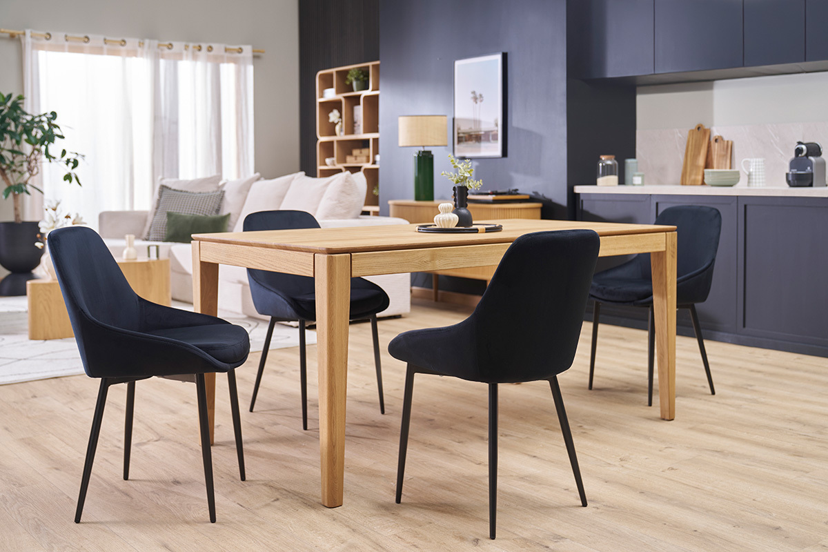 Salle � manger avec chaises design noires en velours et m�tal autour d'une table en bois.