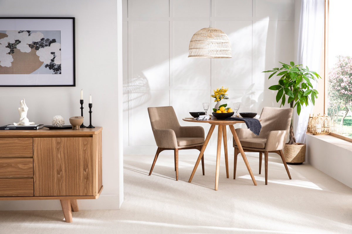 Chaises en tissu beige et bois fonc�, lot de 2, autour d'une table ronde en bois, int�rieur lumineux.