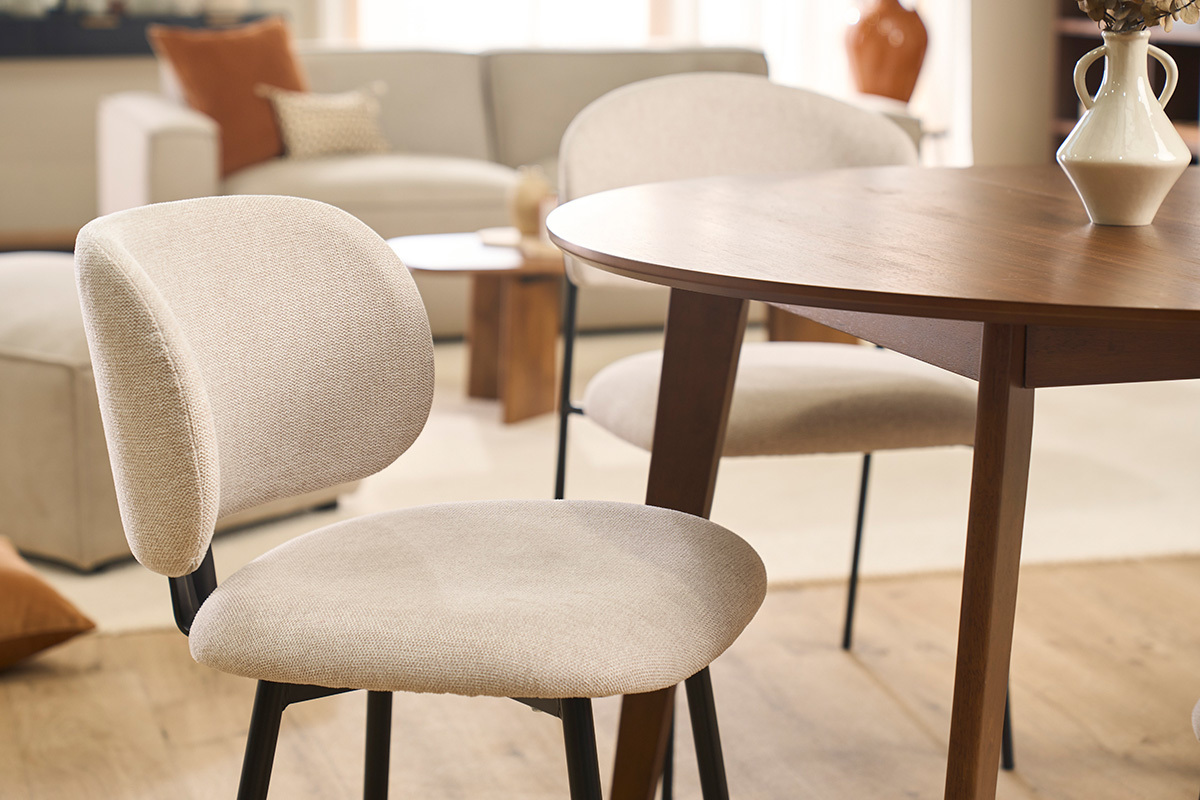 Chaises beige en tissu avec pi�tement en m�tal noir autour d'une table en bois, vue partielle.