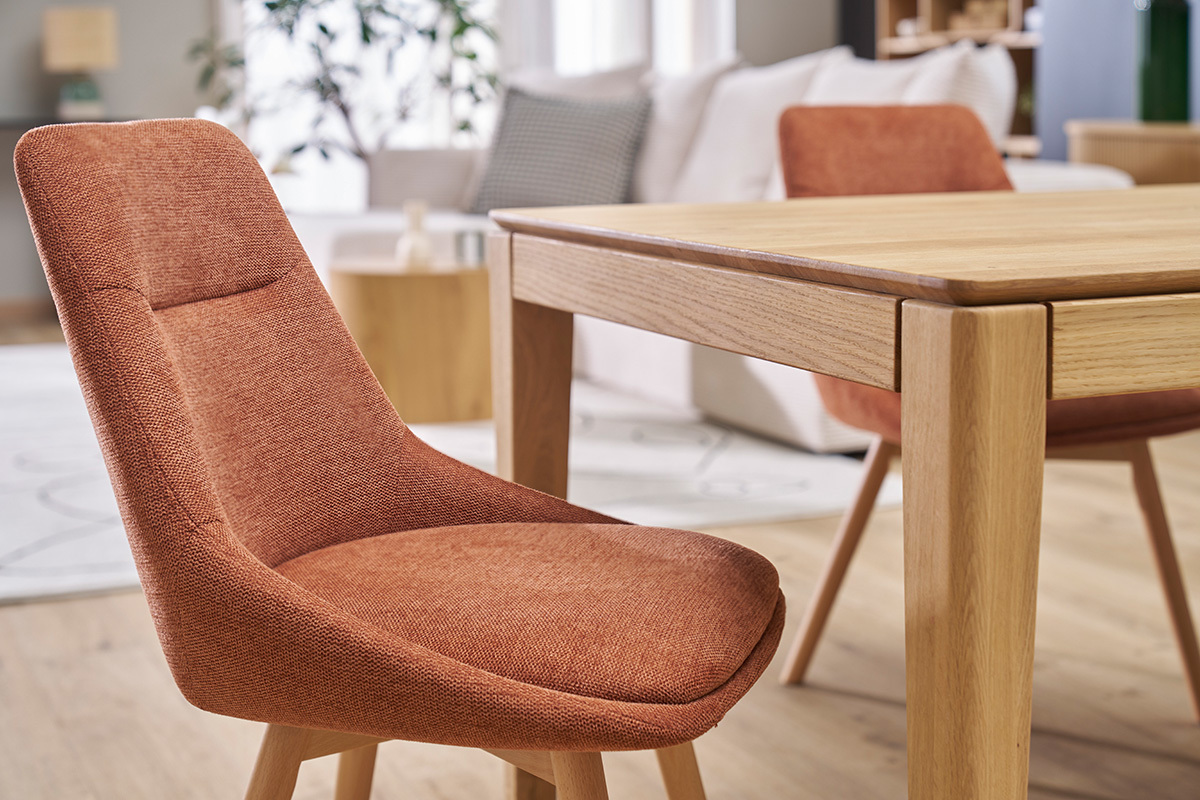 Chaises en tissu effet velours terre br�l�e et pieds en bois clair autour d'une table.