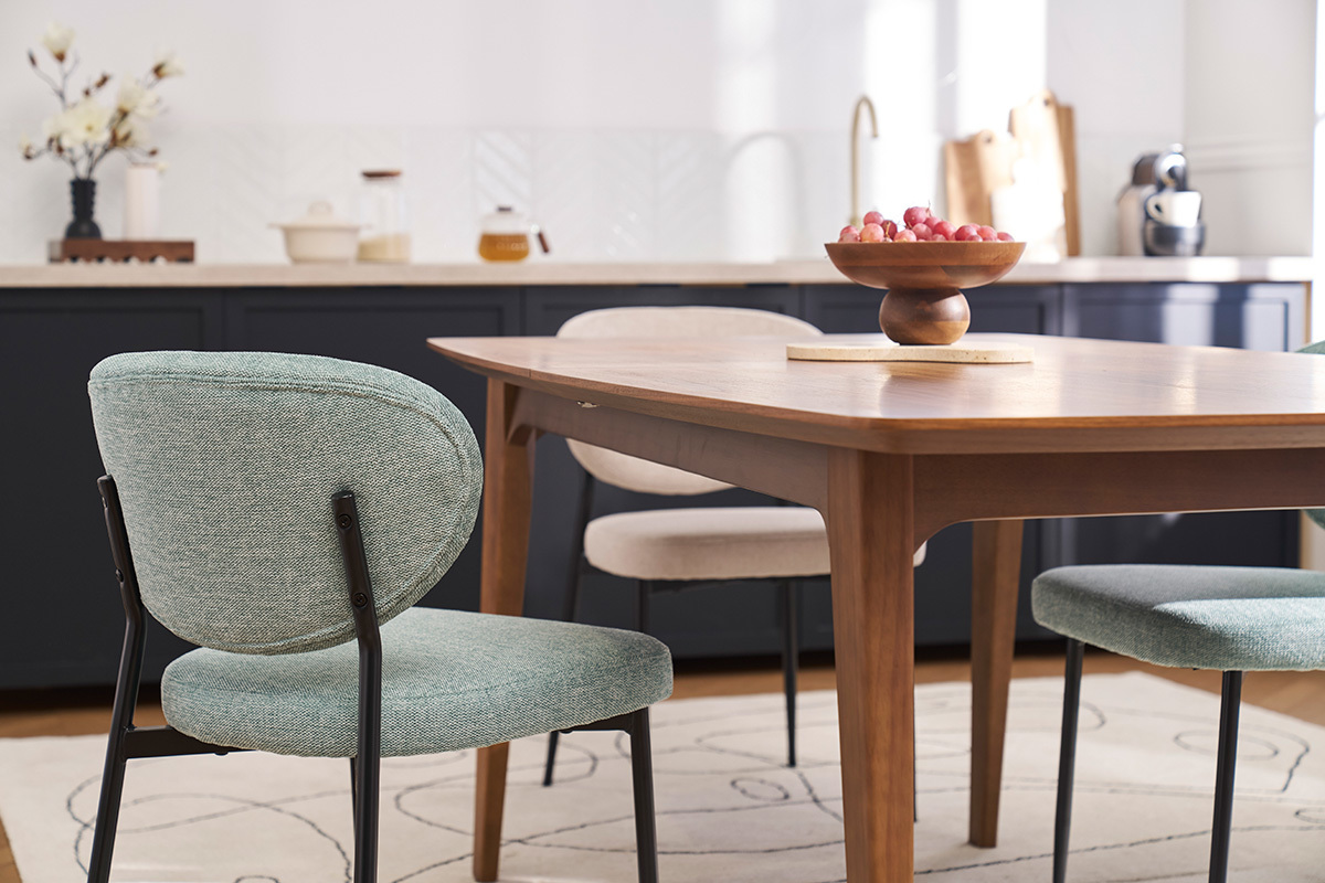 Chaises BREKA en tissu c�ladon et m�tal noir entourant une table en bois, vue int�rieure.