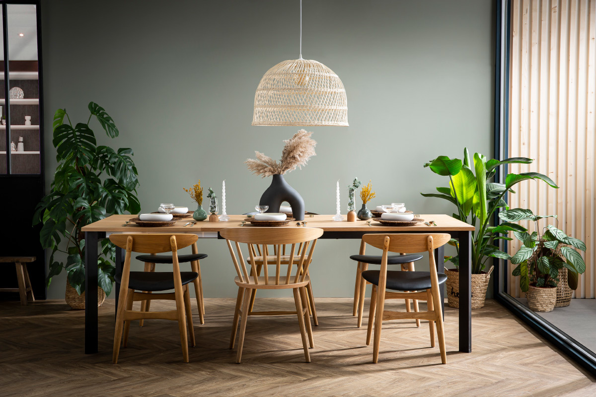 Chaises scandinaves en bois clair et noir autour d'une table en bois.