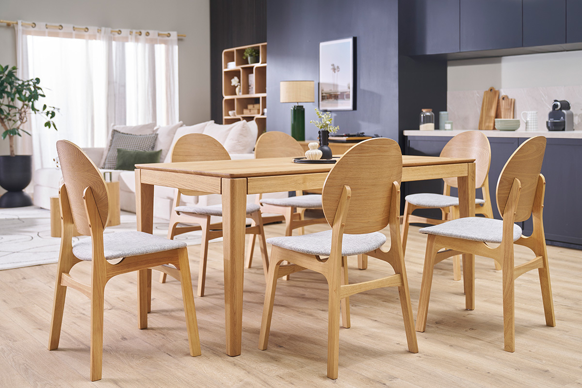 Salle � manger avec chaises scandinaves en bois clair et tissu gris autour d'une table en bois.
