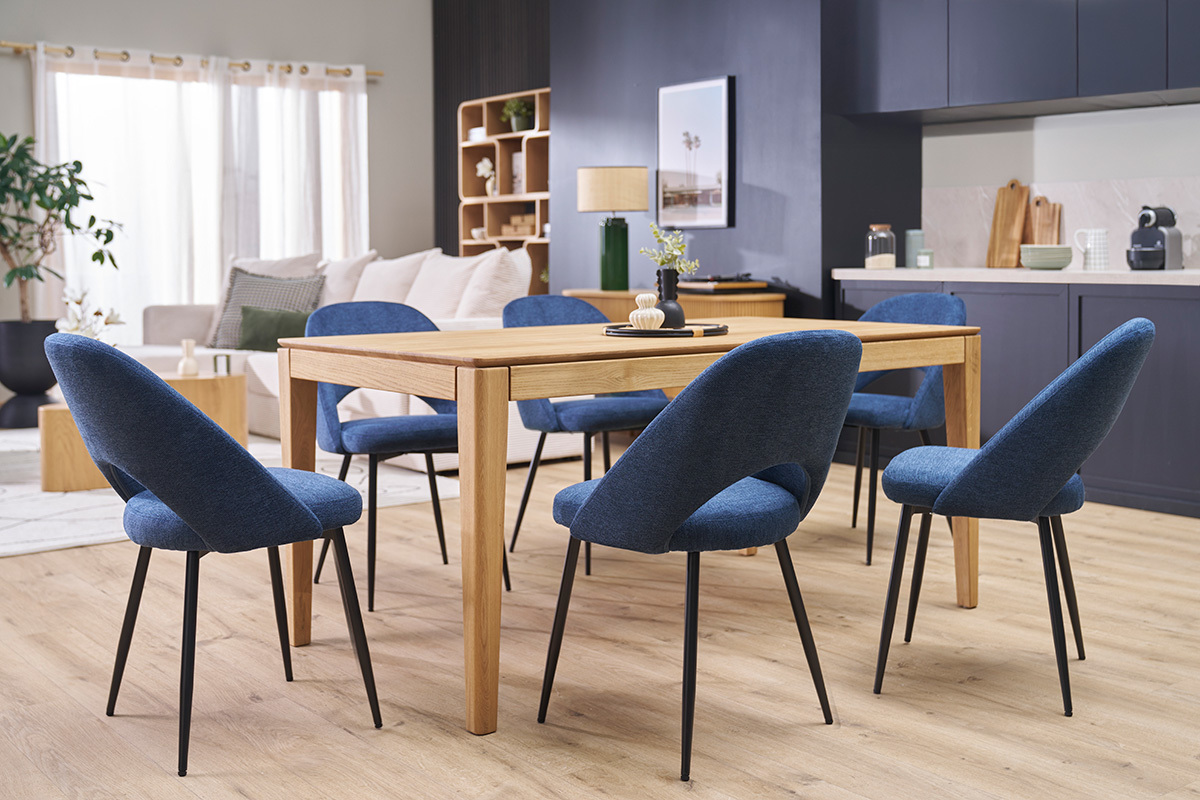 Chaises vintage bleues en tissu velours et m�tal noir autour d'une table en bois dans une salle moderne.