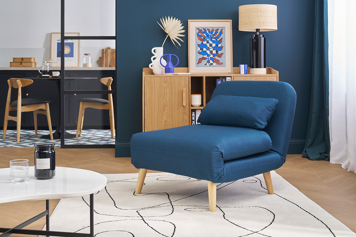 Fauteuil convertible bleu fonc� AMIKO devant une �tag�re en bois, vue de face.