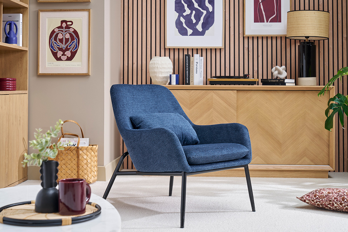 Fauteuil bleu en tissu velours avec pieds en m�tal noir dans un salon moderne.