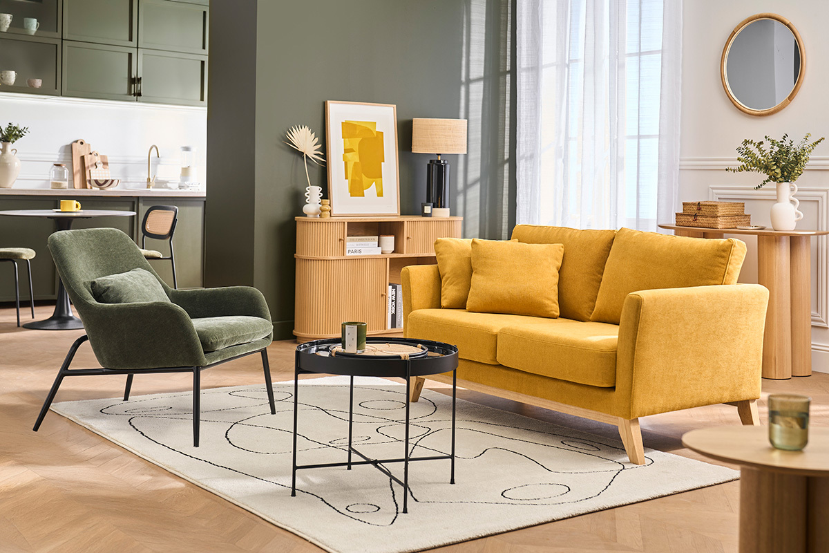 Fauteuil vert kaki en tissu effet velours avec pieds noirs, � c�t� d'un canap� jaune dans un salon moderne.