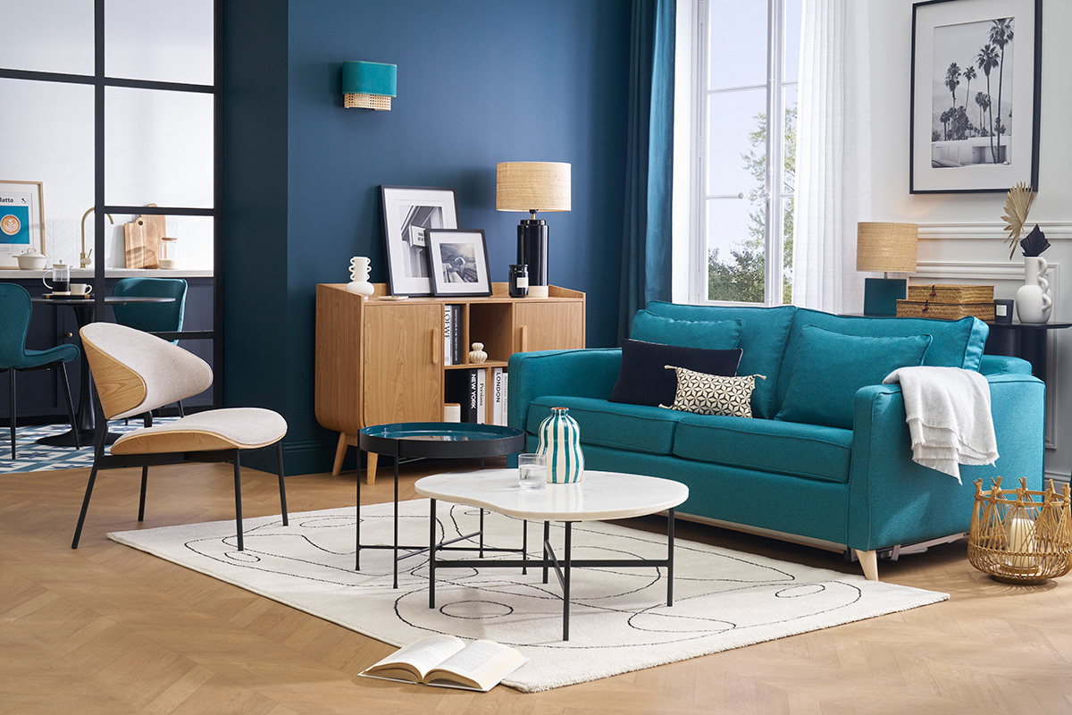 Fauteuil beige en tissu dans un salon avec canap� bleu et table basse.