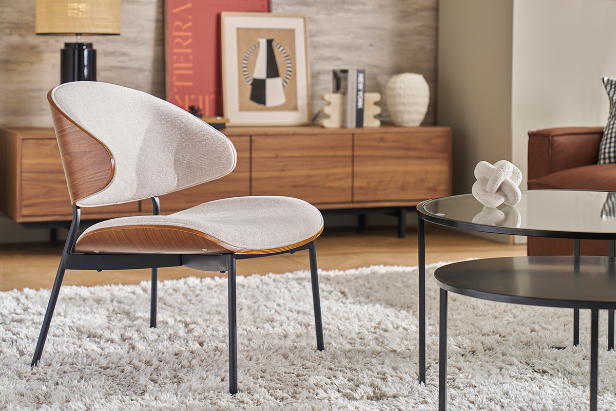 Fauteuil beige en tissu effet velours, bois fonc� et m�tal noir dans un salon moderne.