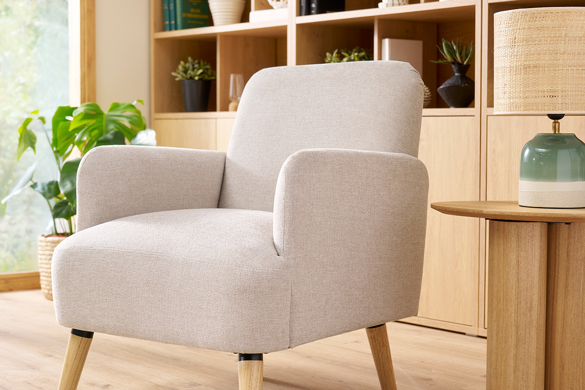 Fauteuil scandinave beige en tissu effet velours avec pieds en bois, vue de 3/4.