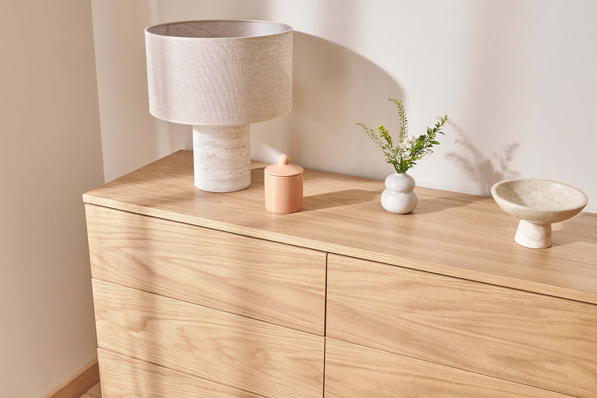 Lampe effet travertin avec abat-jour beige sur commode en bois.