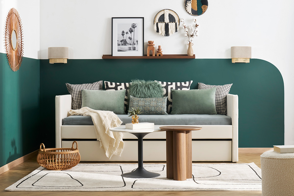 Lit gigogne blanc 90x190 cm ELIE, coussins verts et tables d'appoint sur fond mural vert et blanc.