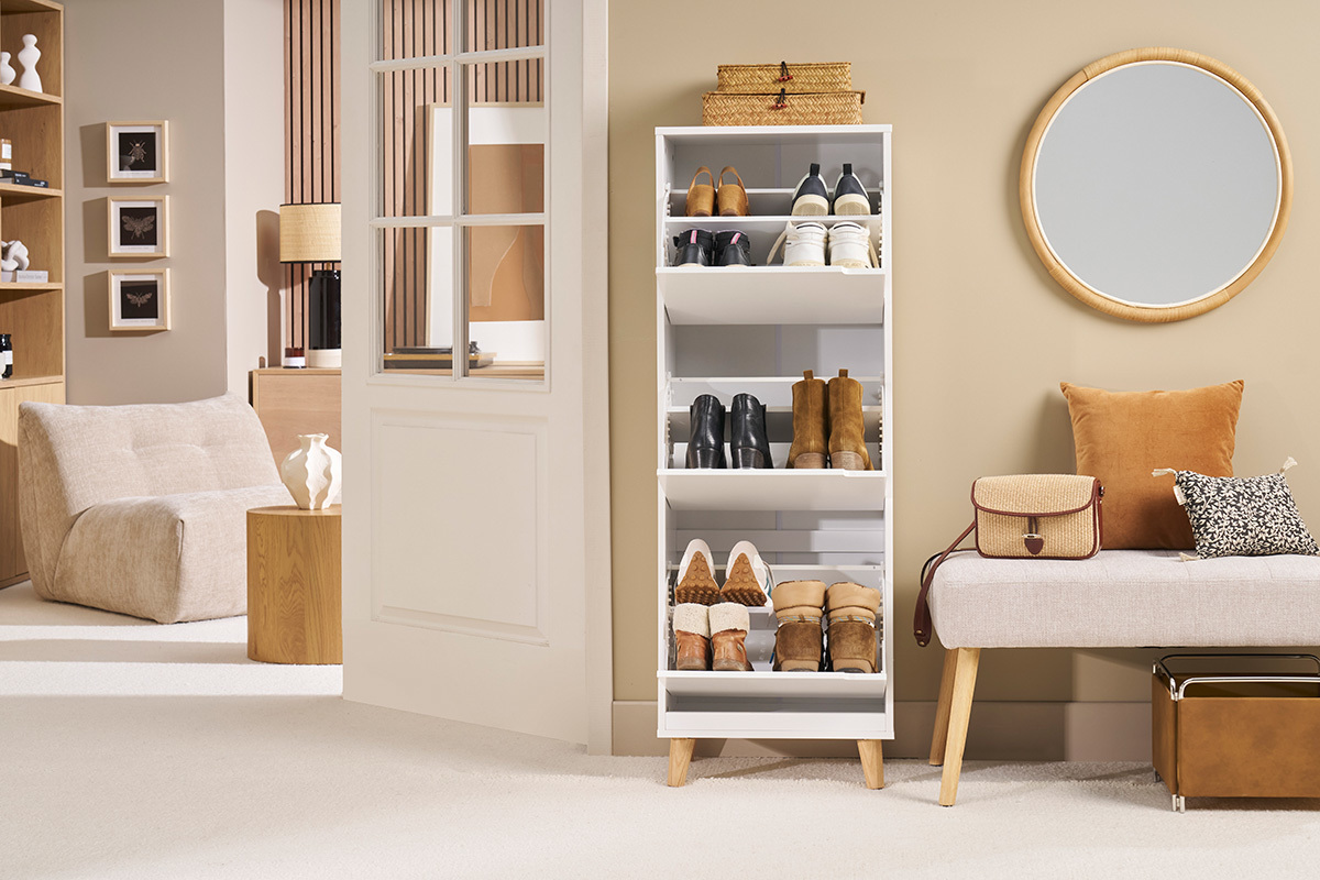 Meuble � chaussures blanc avec 3 casiers et pieds en ch�ne, rempli de chaussures, dans un int�rieur moderne.
