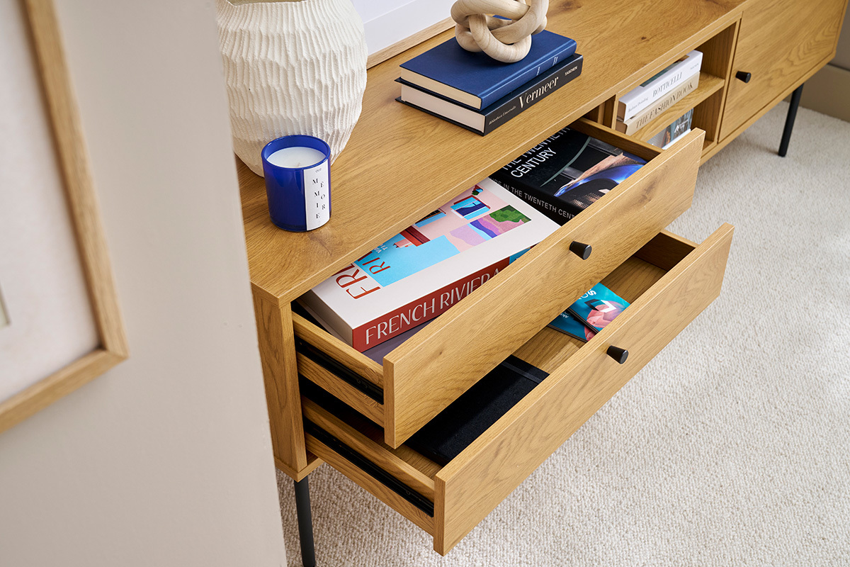Meuble TV en bois clair avec tiroirs ouverts, livres et objets d�co sur le dessus.