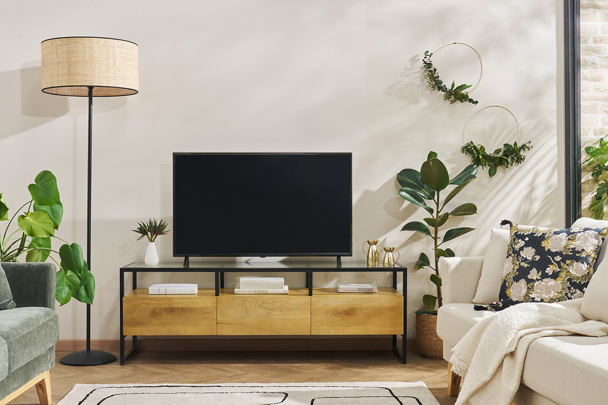 Meuble TV en bois manguier et m�tal noir, vue de face avec plantes et canap� environnants.