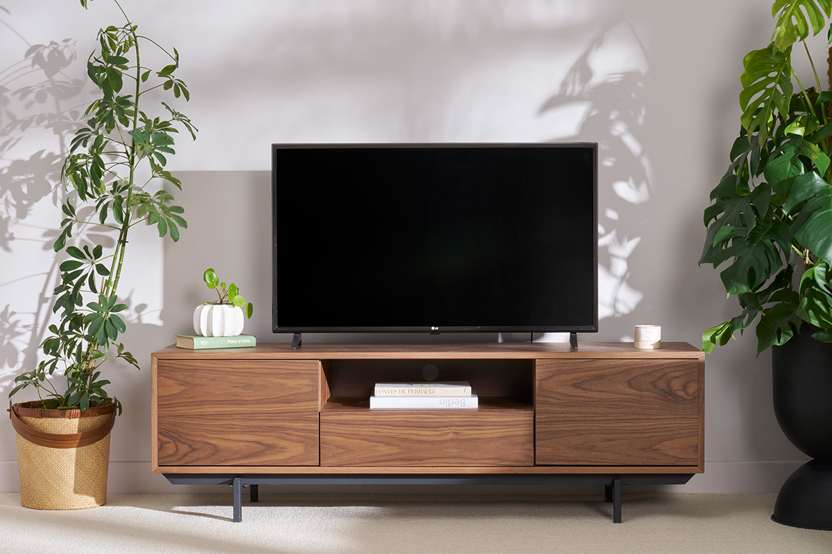 Meuble TV vintage en bois fonc� avec niche ouverte, t�l�vision dessus, plantes de chaque c�t�.