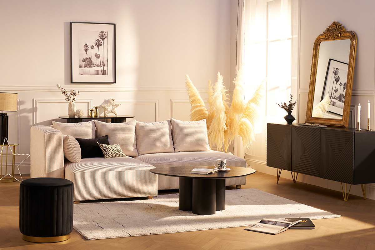 Salon moderne avec un pouf rond en velours noir et m�tal dor� � c�t� d'un canap� beige.