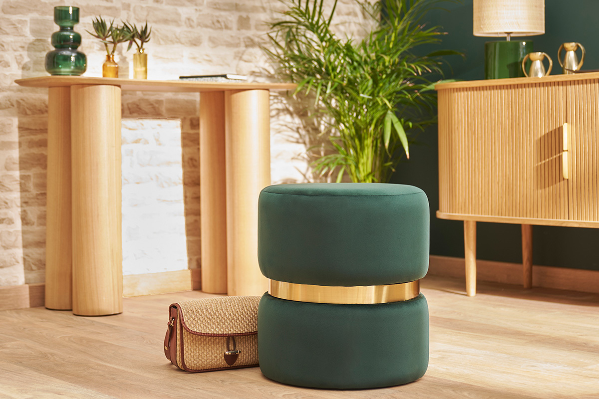 Pouf rond en velours vert fonc� avec bande dor�e dans un int�rieur lumineux.