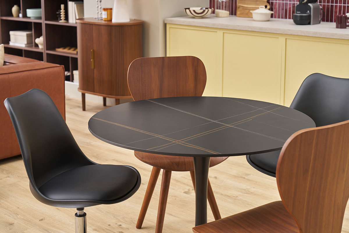Table ronde en c�ramique noire et m�tal avec des chaises, vue d'ensemble dans un int�rieur.