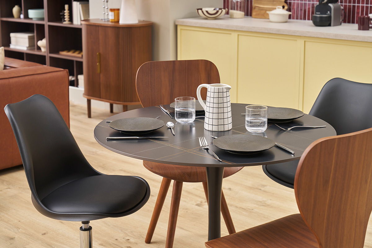 Table ronde en c�ramique noire et m�tal avec couverts, vue de dessus.