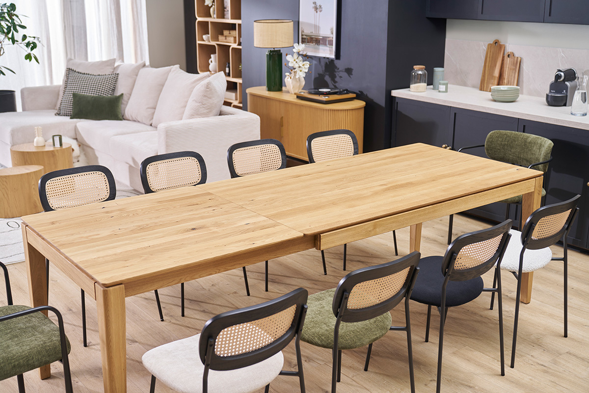 Table � manger extensible en ch�ne clair avec chaises noires autour, vue en int�rieur.