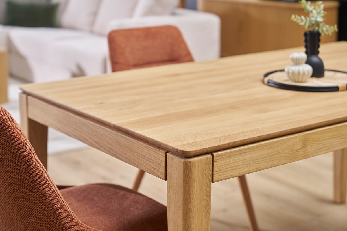 Table � manger en ch�ne clair, vue rapproch�e, avec chaise en tissu rouge.