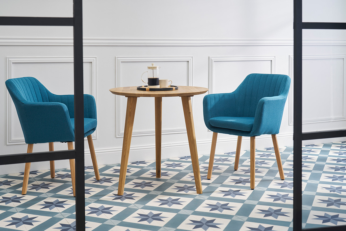 Table ronde en ch�ne massif avec chaises bleues sur sol � motifs.