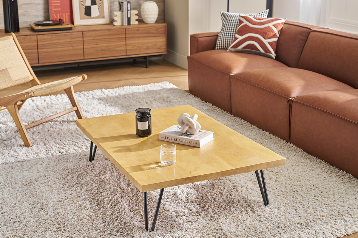 Table basse VIBES en bois de manguier et m�tal, vue de trois-quarts, dans un salon avec canap� et fauteuil.