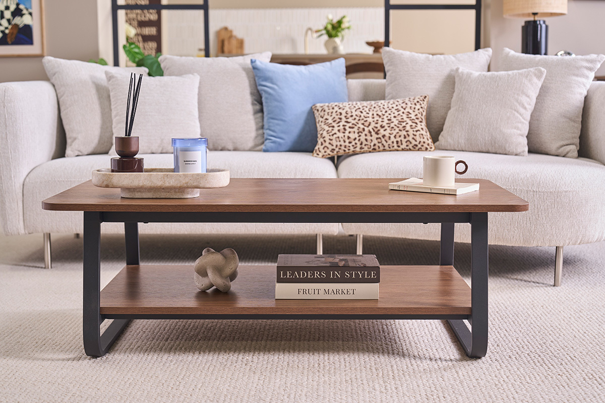 Table basse rectangulaire en bois noyer et m�tal avec plateau inf�rieur, vue de face � c�t� d'un canap�.