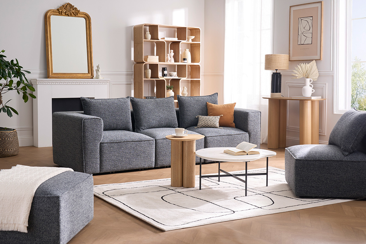 Table d'appoint bois clair HOLLEN dans un salon moderne, entre deux canap�s gris.